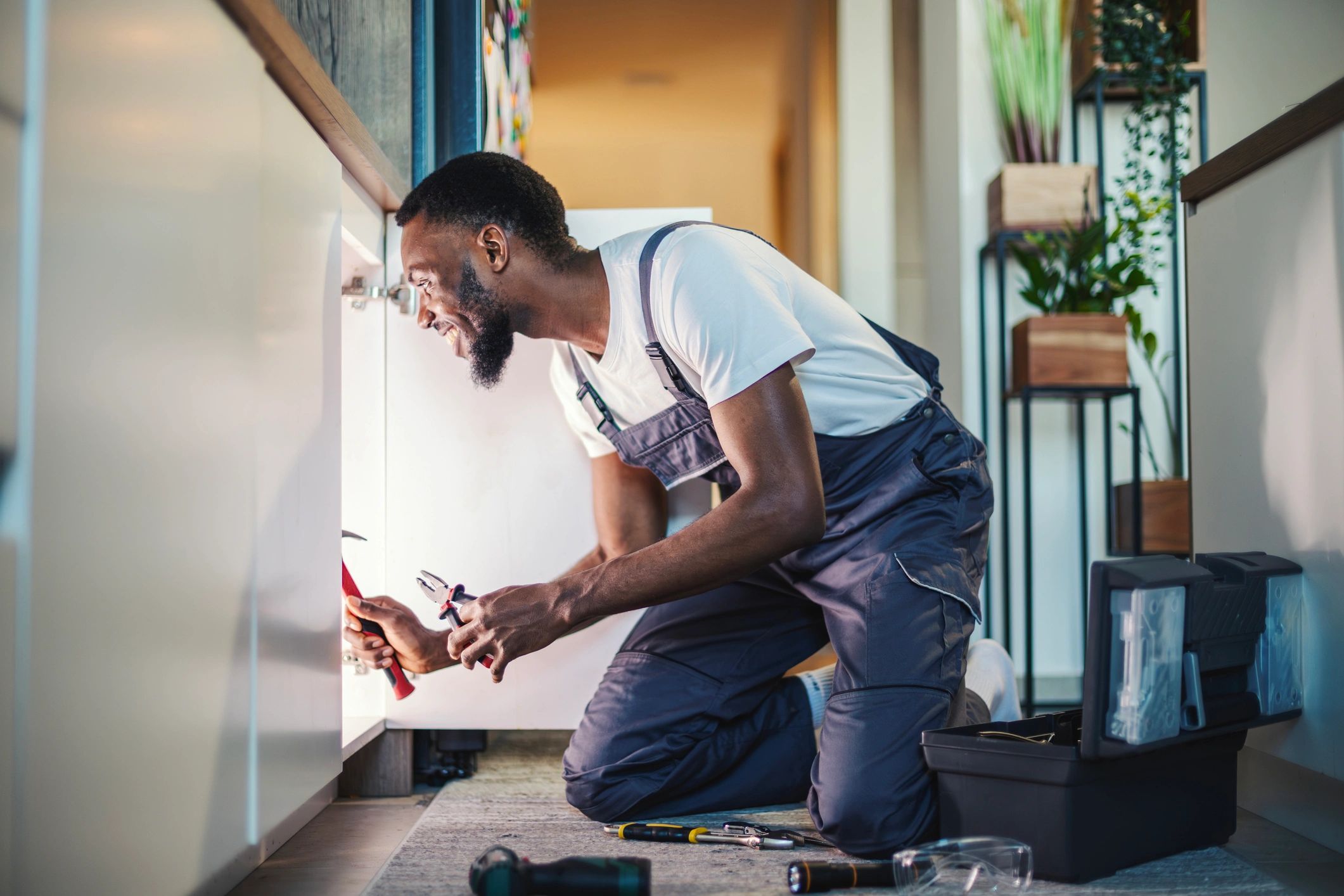Handyman repairing plumbing under a kitchen sink